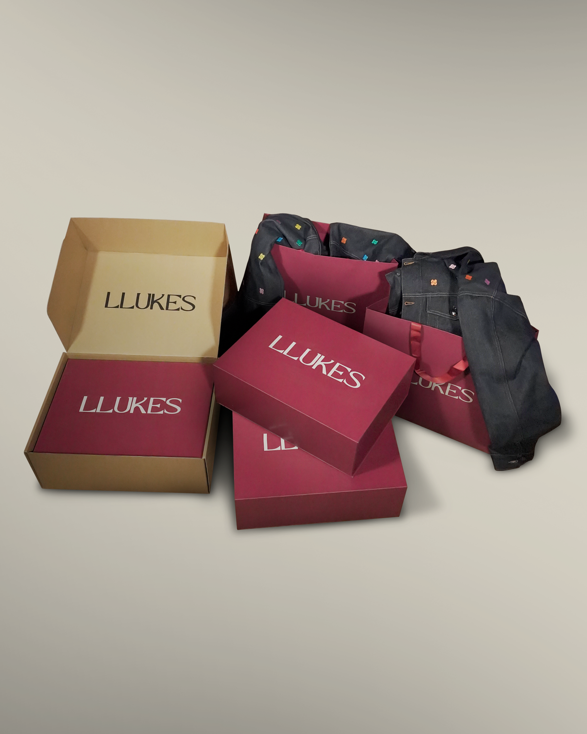 Boîtes et sacs LLUKES bordeaux accompagnés des pièces en denim de la collection.